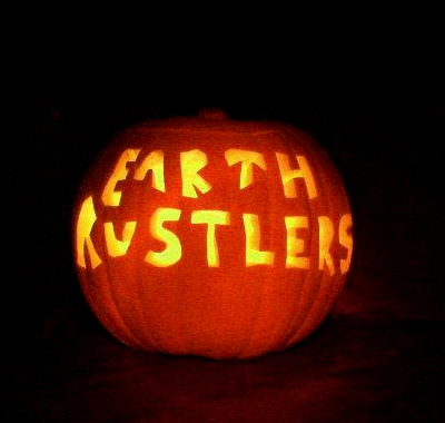 A pumpkin with Earth Rustlers carved into it and a lit candle inside