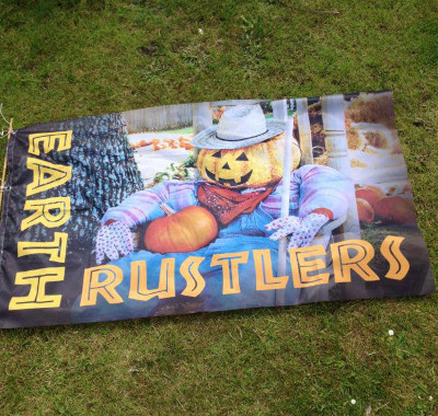 A flag featuring the band name Earth Rustlers and a pumpkin scarecrow 